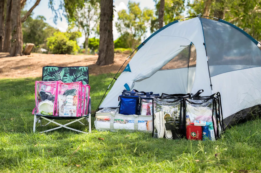 Clear camping storage bags packed outside a tent with clothes and travel gear