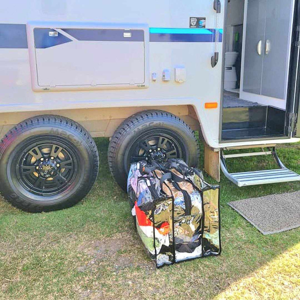 Large black campaq clear bag packed with clothes sitting outside  camper trailer