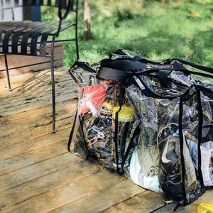 Large black trim clear camping bag filled with camping gear sitting on timber floor of deck