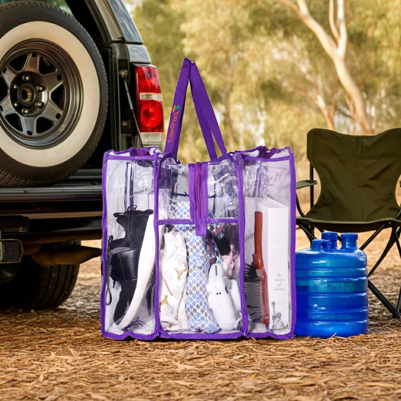 Large purple trim clear CamPaq camping bag  filled with camping supplies next to a vehicle and chair outdoors