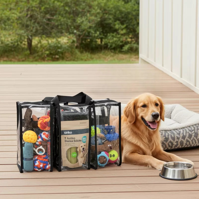 Dog sitting on a wooden deck beside medium black trim clear bag containing dog toys and treats