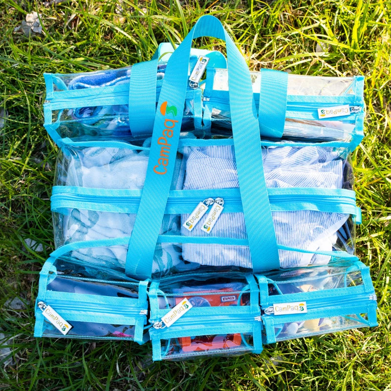 Medium blue clear CamPaq camping bag showing view from top with gear and handles and  brand logo on grass