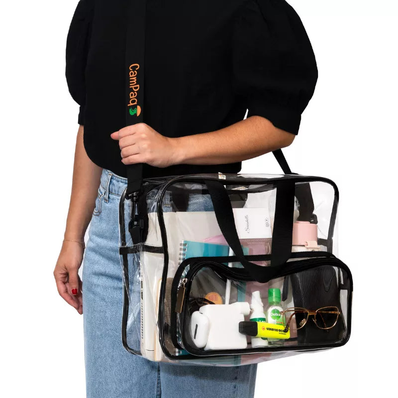 Person holding a clear work/travel bag with various items inside, with a shoulder strap with 'CanPaq' branding.