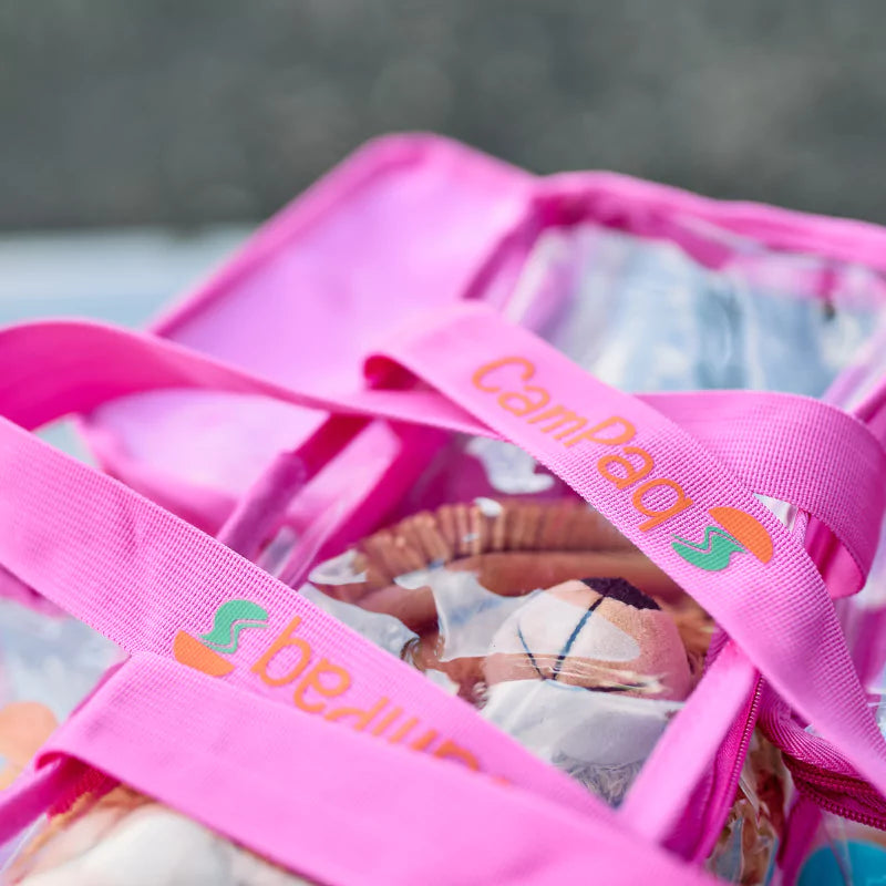 Clear hot pink CamPaq toiletry bag with CamPaq branding containing toiletries