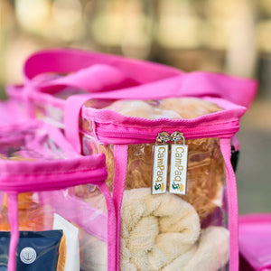 Clear hot pink toiletry bag with a clear compartment containing towels and visible zipper tags CamPaq label.