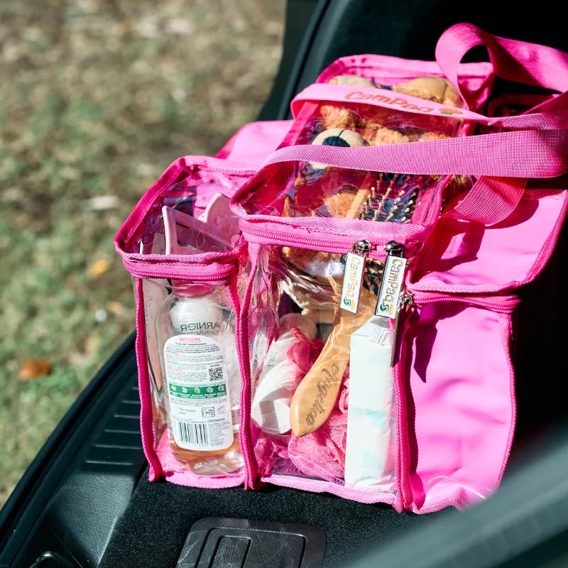 Hot pink clear CamPaq toiletry bag with opaque pocket filled with toiletry items