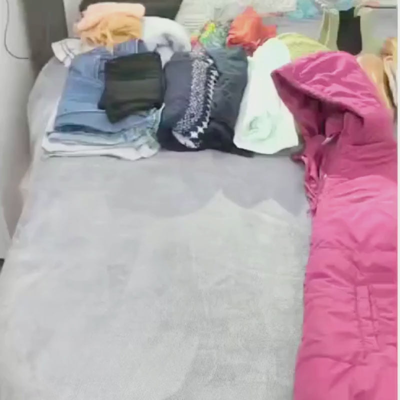 Video of large purple clear CamPaq camping bag being packed on bed with clothes