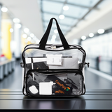 Clear campaq work bag with laptop and business items with black handle and on a table in an airport setting